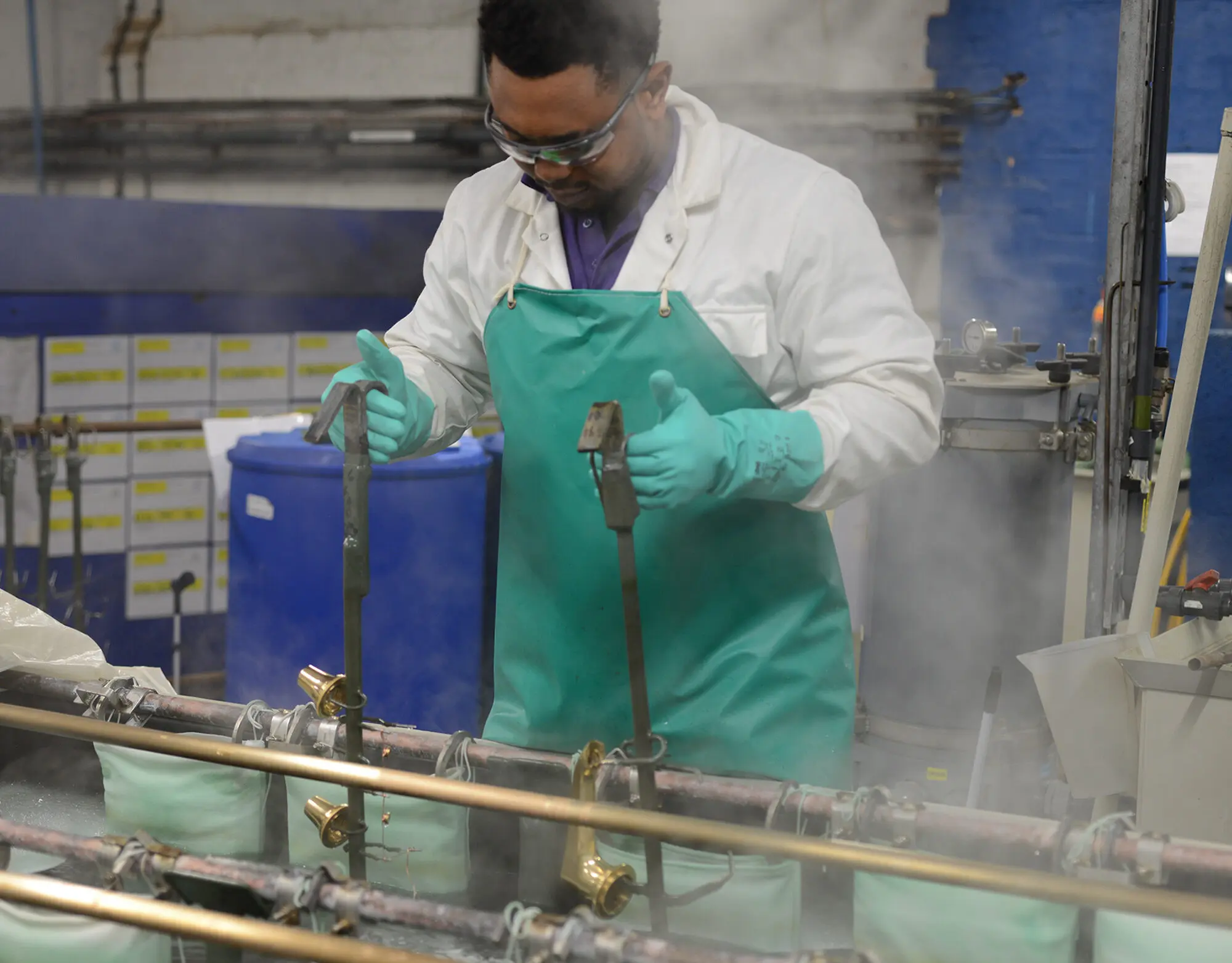 A person at work dipping brassware in the Samuel Heath electroplating shop