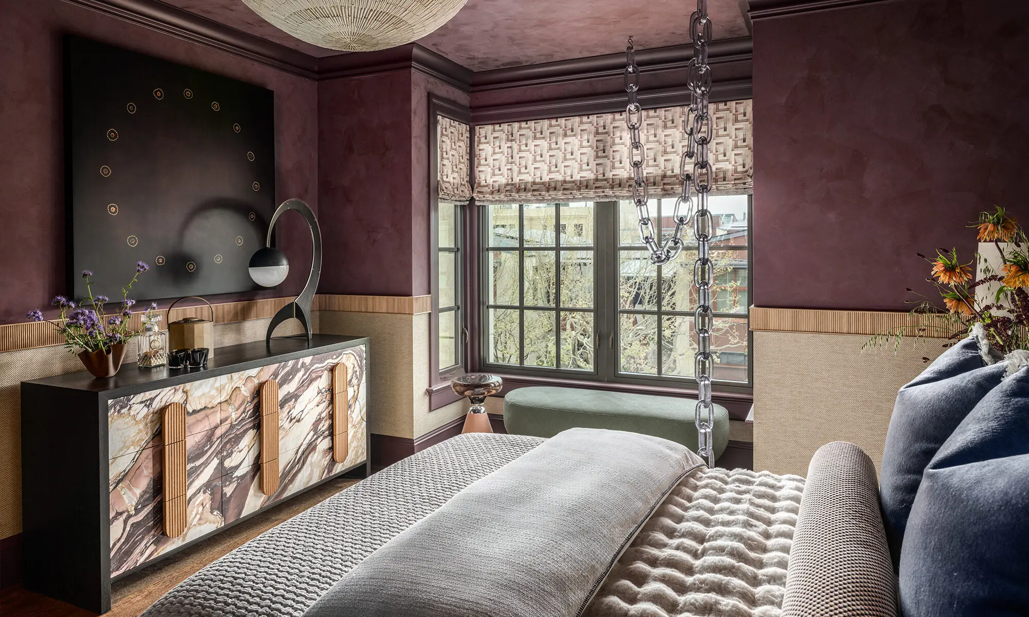 Middle of bed view in The Global Nest bedroom facing curated furniture and a large window