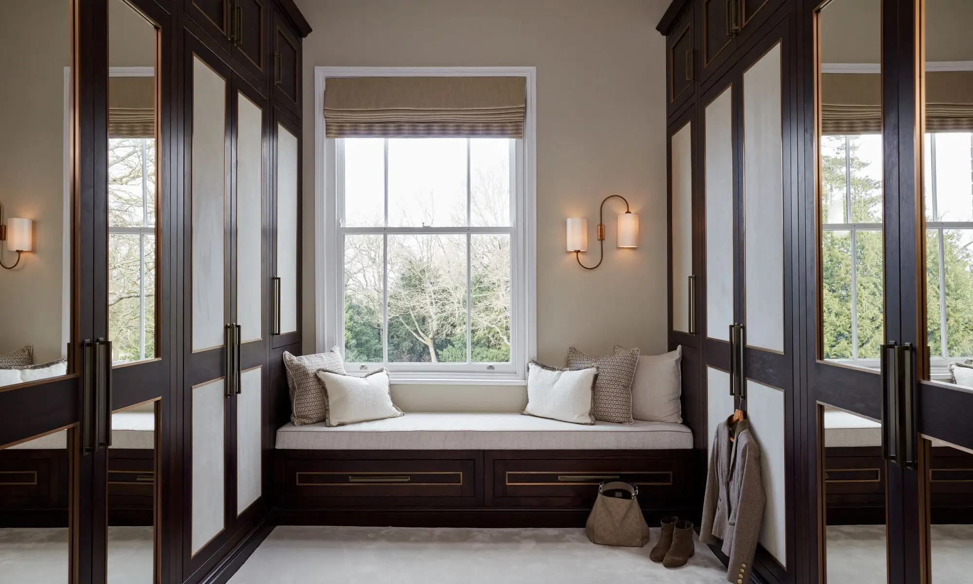 A walk in closet with a bench and window.