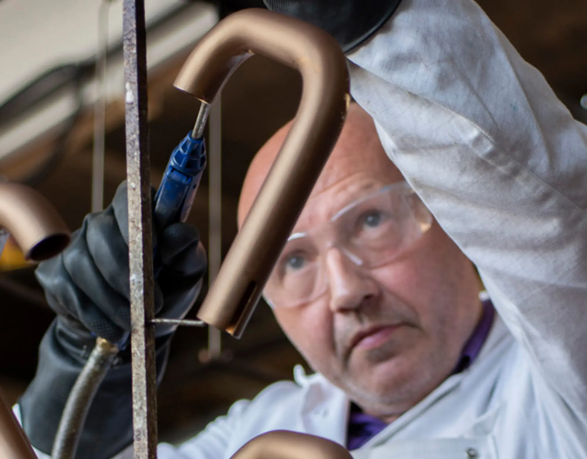A lacquering technician removing excess air from a metal holder with tap spouts