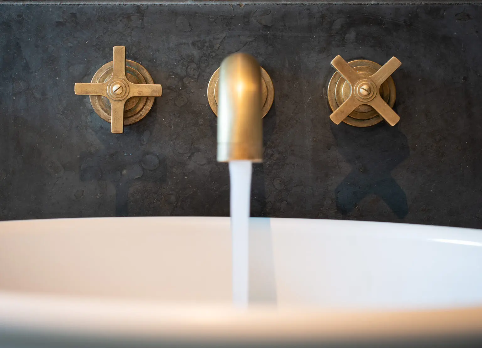 Samuel Heath Bauhaus inspired Landmark Pure wall mounted tap in a natural urban brass finish showing patina.