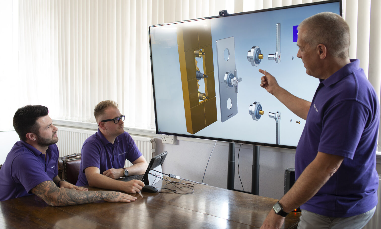 Assembly department manager presents brass prototype instructions to design engineers.
