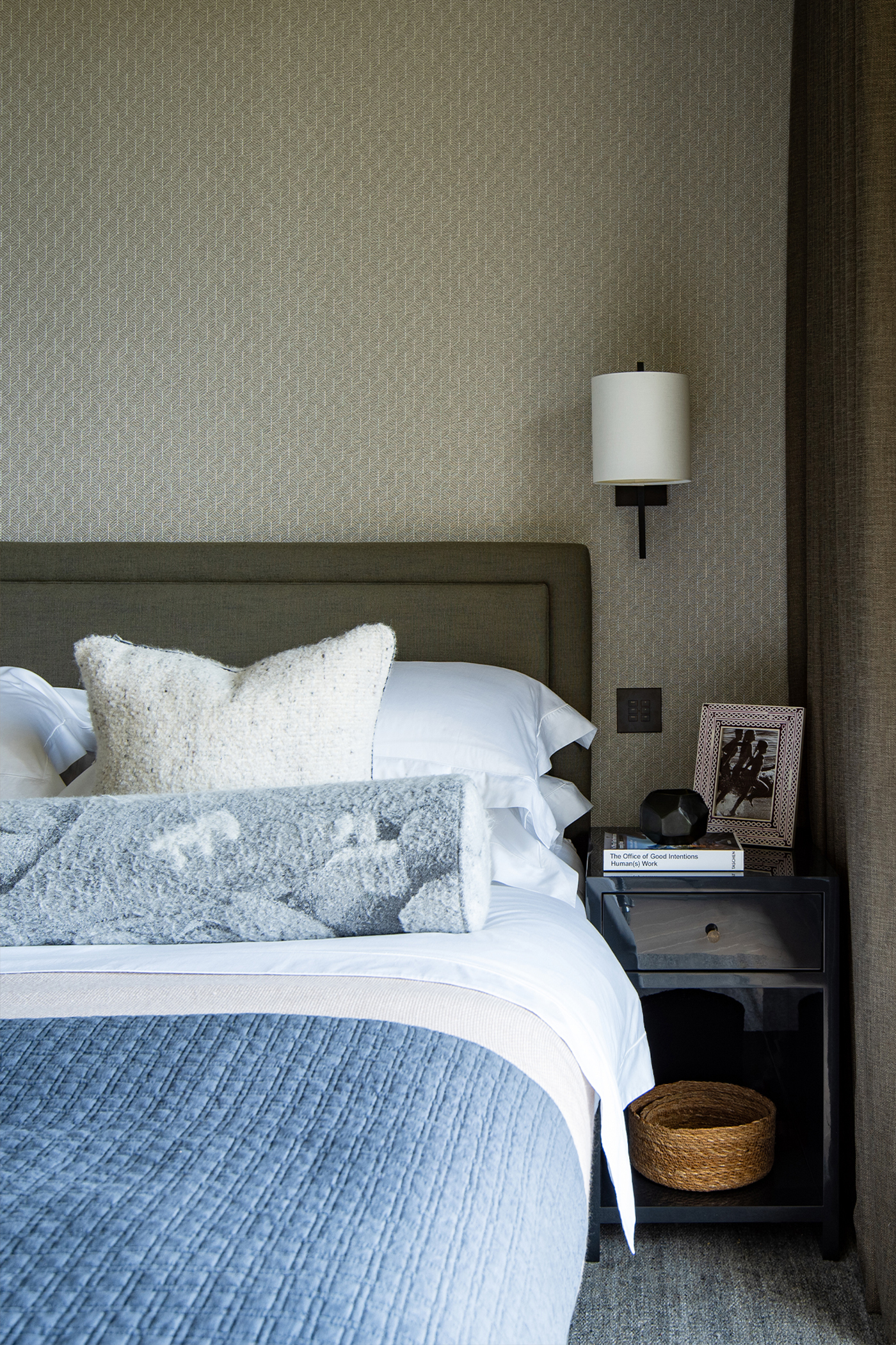 Bedroom with blue textured covers and fabric wall covering