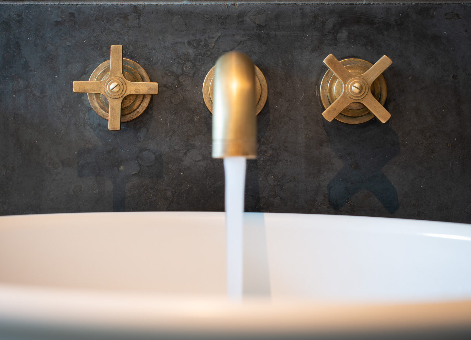 Samuel Heath Bauhaus inspired Landmark Pure wall mounted tap in a natural urban brass finish showing patina.