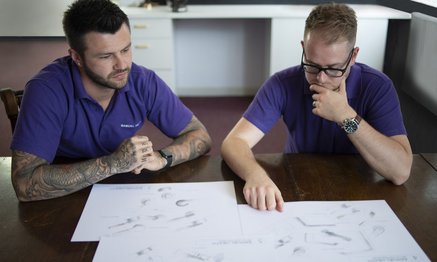 Two design engineers inspect sketches supplied by the product designer.