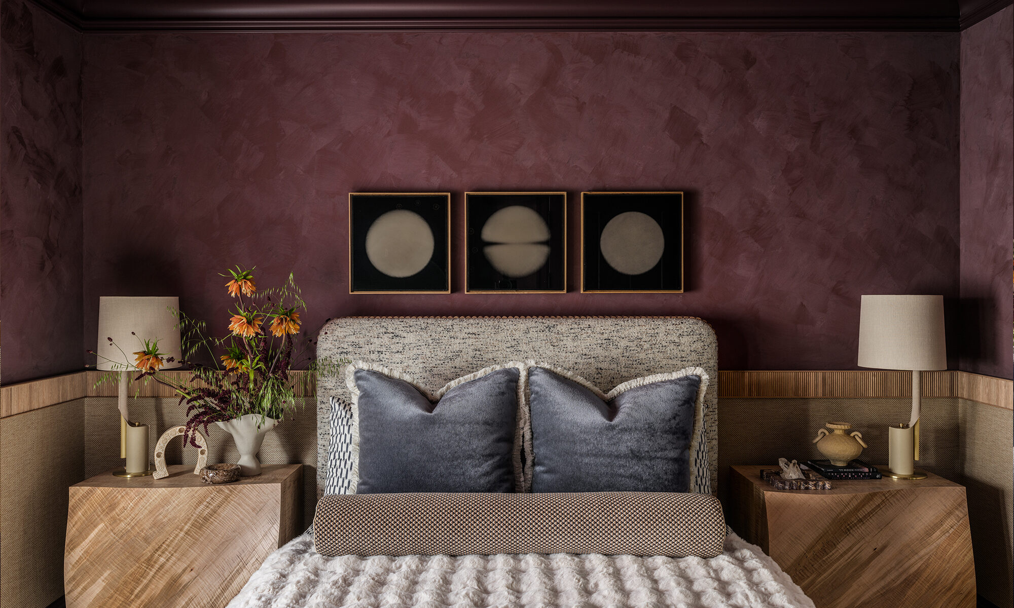 End of bed view in The Global Nest bedroom facing a bespoke headboard and wood side tables