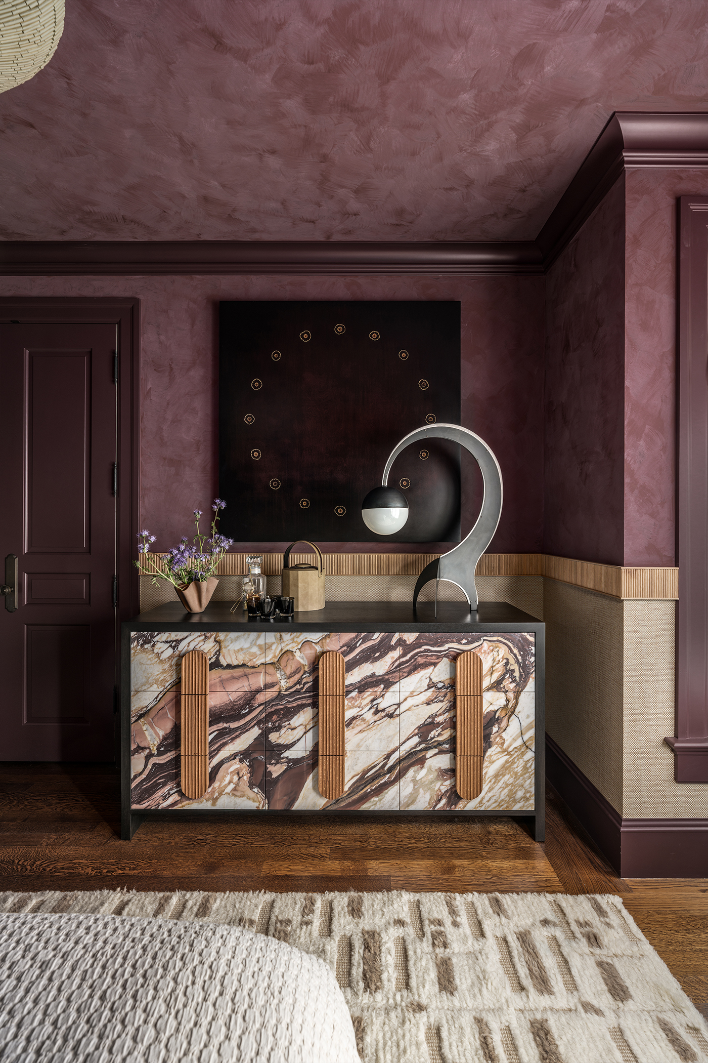 End of bed view in The Global Nest bedroom facing a marble pattern chest of drawers