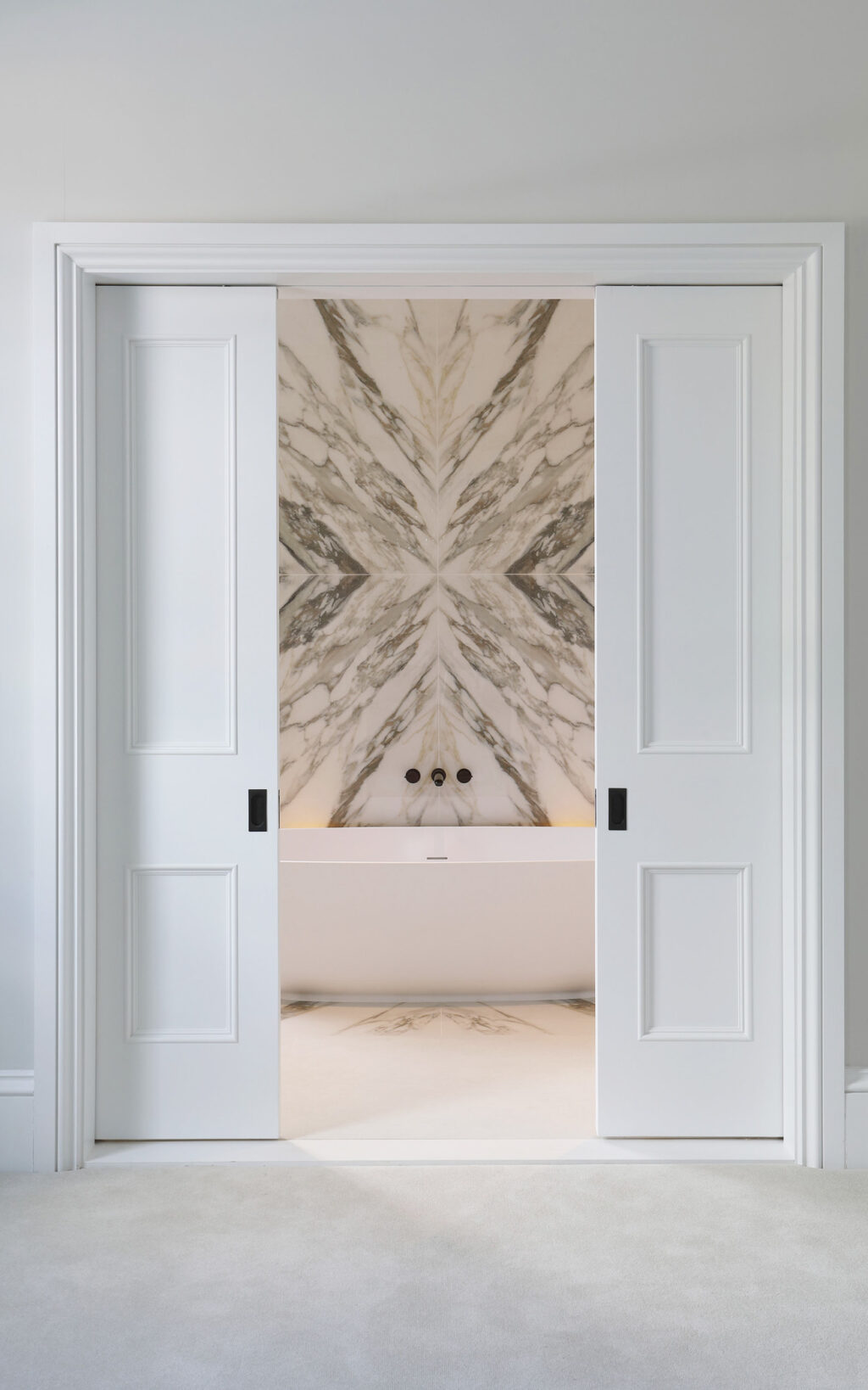 Door opening to show Samuel Heath bath tap and bookmatched marble